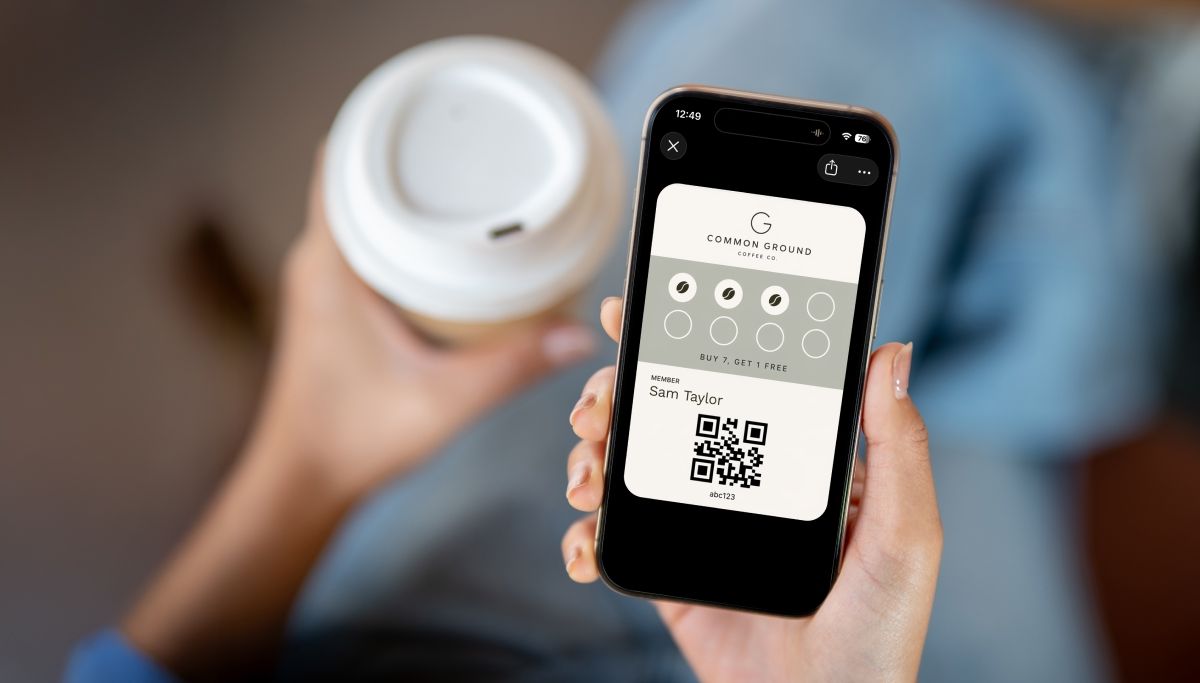 A printed Coffee Corner loyalty card on a cafe counter while a customer scans the QR code with their phone